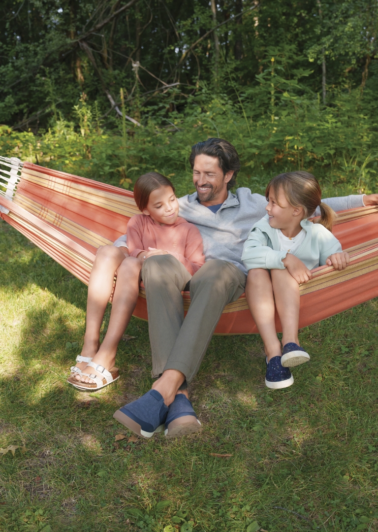 The featured image is a man wearing Nunn Bush shoes while on a hammock with his daughters.