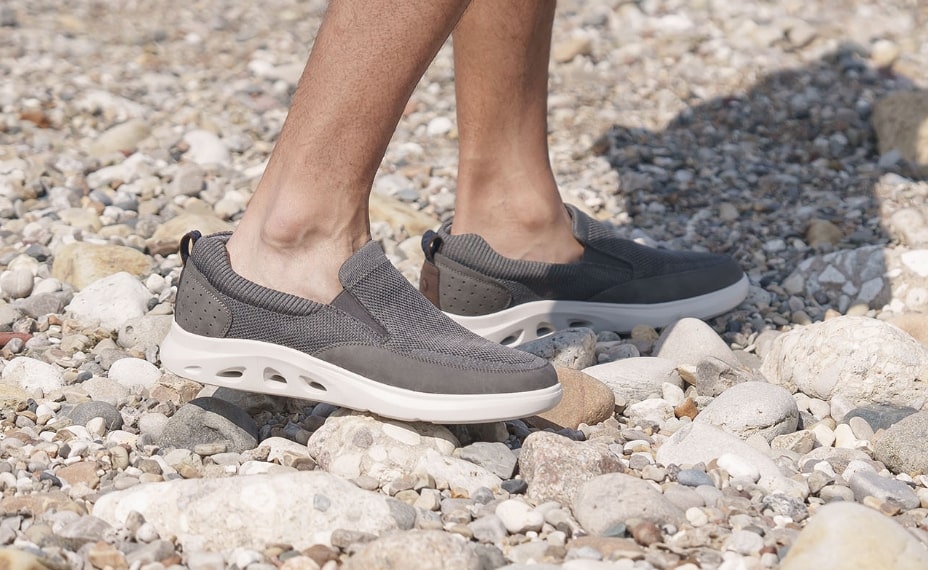 Image features the Ponte slip on in grey on a rocky beach.