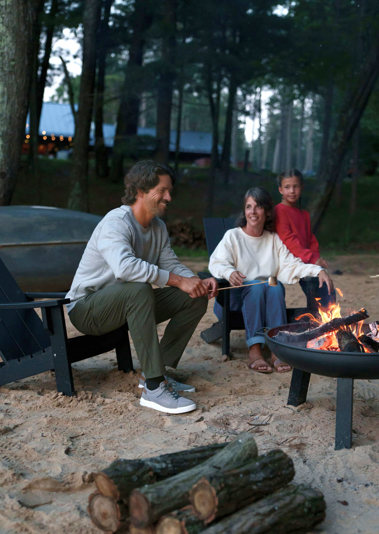 The featured image is a man wearing Nunn Bush KORE City Rally Mesh Sneakers in gray multi while sitting around a bonfire with his family in a wooded beach area. 
