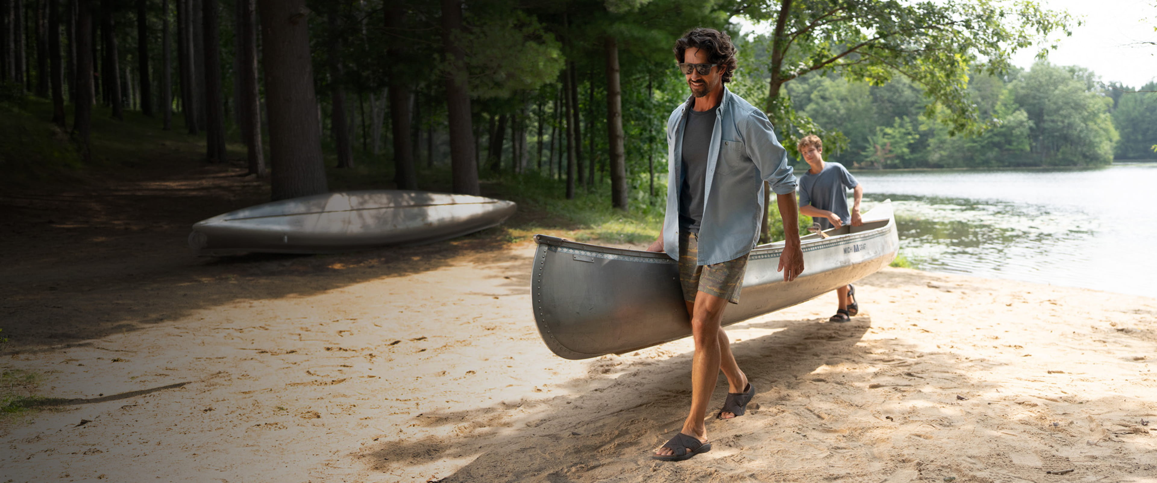 Shop our new arrivals featuring a man and son carrying a canoe up a beach in sandals.