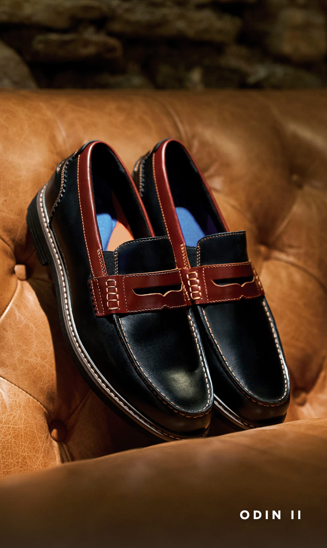 Men's Dress Shoes category Image features the Odin II in black on a cognac leather sofa.