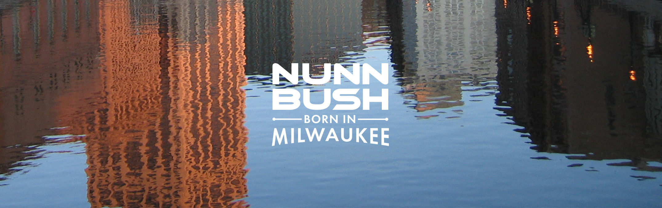 Nunn Bush, Born in Milwaukee. The featured image is the Milwaukee River with buildings reflected in the water.